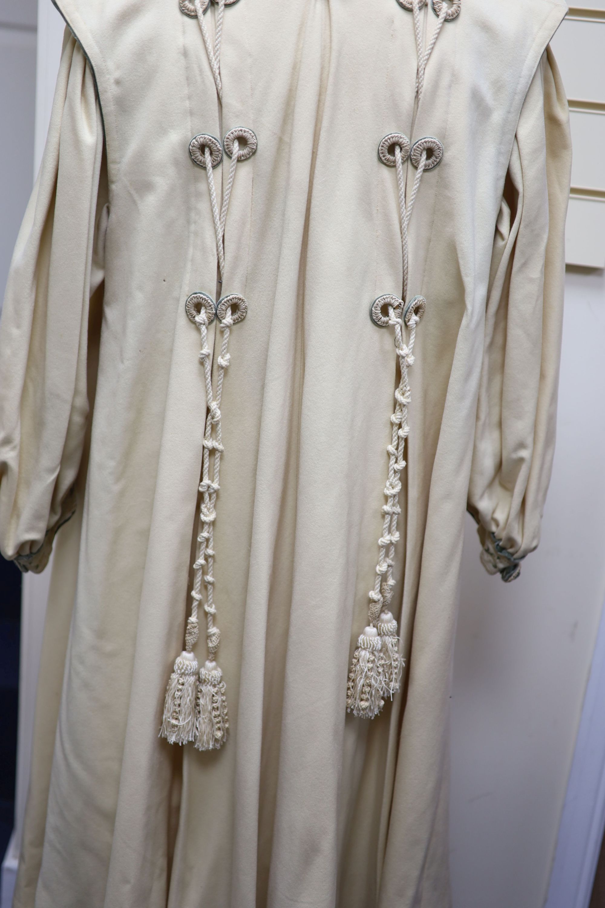 An Edwardian ladies fine cream wool coat with embroidered cuffs front edging and collar and ornate corded tasselling,